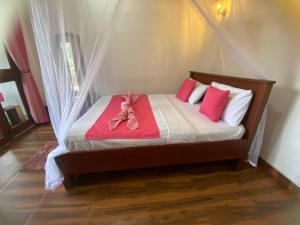 a bedroom with a bed with red and white pillows at Happiness Cottage in Ella