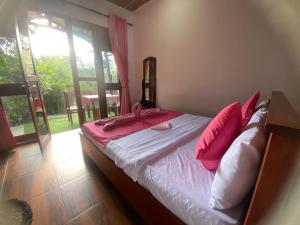 a bedroom with a bed with pink pillows on it at Happiness Cottage in Ella +10 photos