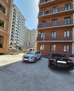 two cars parked in a parking lot in front of a building at One-Bedroom Apartment in Fergana
