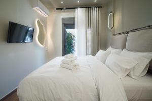 a bedroom with a white bed with towels on it at Olive City Suites in Larisa