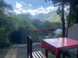 a table with a red table cloth sitting on a porch with a view at Happiness Cottage in Ella