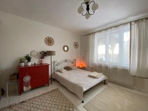 a bedroom with a bed with a red dresser and a window at Królewska Sielanka in Mielnik