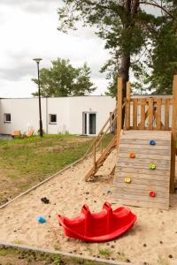 a wooden playground with a slide in the sand at Przystań Kormoran in Czarna Wieś
