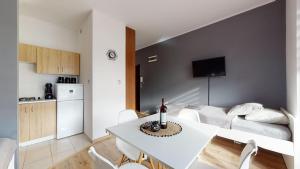 a living room with a white table and a kitchen at Apartament Fibra Crema in Rybnik
