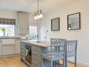 a kitchen with a sink and a counter with two chairs at Fern House in Hinderwell
