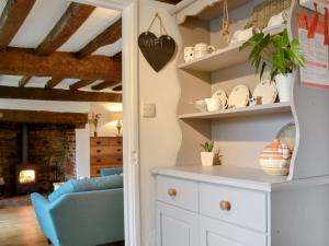 a kitchen with white cabinets and a blue chair at Three Ash Cottage in Bungay
