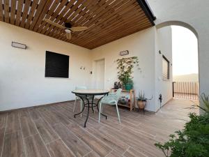 a patio with a table and chairs and a ceiling at The Peleg Tal Unit - היחידה בפלג טל in Dafna