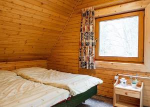 a bed in a wooden room with a window at Chata Malino in Ružomberok