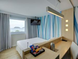 a hotel room with a bed and a desk and a window at Mercure Rio de Janeiro Barra da Tijuca in Rio de Janeiro +178 photos