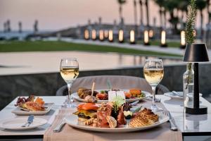 a table with plates of food and glasses of wine at Chrysomare Beach Hotel & Resort in Ayia Napa