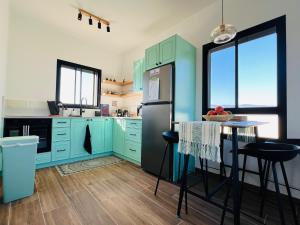 a kitchen with blue cabinets and a refrigerator at The Peleg Tal Unit - היחידה בפלג טל in Dafna +7 photos