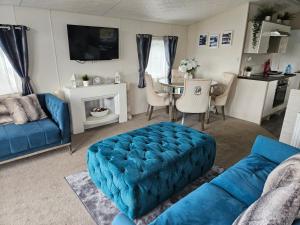 a living room with a blue couch and a table at Foxwood Lodge Private Hot Tub Getaway in Swarland