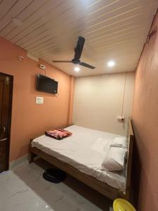 a small bed in a room with a ceiling fan at Hotel Chilika in Bālugān