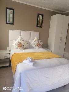 a bedroom with a large white bed with towels on it at Ekhenani Guest House in Nongoma