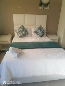 a white bed with pillows and a towel on it at Ekhenani Guest House in Nongoma
