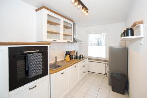 a kitchen with white cabinets and a black appliance at Quartier VierGlück in Marl