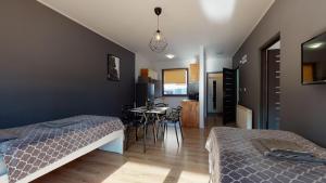 a bedroom with two beds and a dining room with a table at Apartament Fibra Flat White in Rybnik