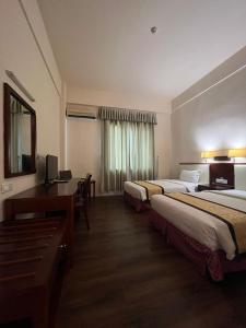 a hotel room with two beds and a desk at Atari Inn Tawau in Tawau