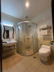 a bathroom with a shower and a toilet and a sink at Atari Inn Tawau in Tawau +18 photos