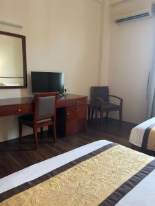 a bedroom with a desk and a bed and a mirror at Atari Inn Tawau in Tawau