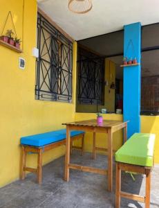 a table and bench in a room with a yellow wall at Urcia Surf House in Huanchaco