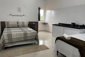 a white room with a bed and a kitchen at Apartamentos Vitória – Conforto e Excelente Localização in Barreirinhas