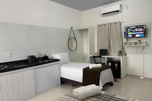 a bedroom with a bed and a kitchen with a sink at Apartamentos Vitória – Conforto e Excelente Localização in Barreirinhas