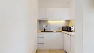 a white kitchen with a sink and a microwave at Studio Fibra Macchiato in Rybnik
