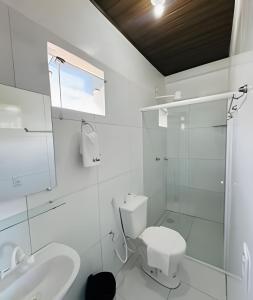 a white bathroom with a toilet and a sink at Apartamentos Vitória – Conforto e Excelente Localização in Barreirinhas