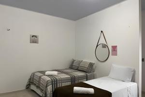 a white room with two beds and a mirror at Apartamentos Vitória – Conforto e Excelente Localização in Barreirinhas