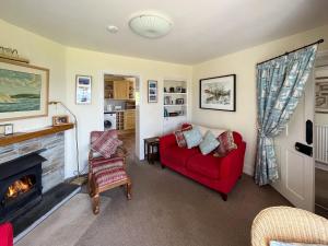 a living room with a red couch and a fireplace at Coastguard Cottage in Downderry