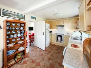 a kitchen with a white refrigerator and wooden cabinets at Coastguard Cottage in Downderry