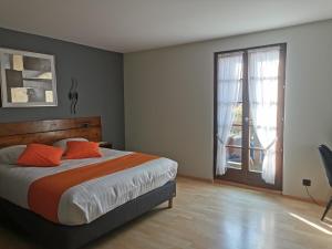 a bedroom with a bed with orange pillows and a window at Hôtel Restaurant AU SOLEIL in Wahlbach