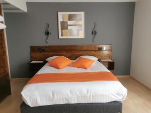 a bedroom with a large bed with two orange pillows at Hôtel Restaurant AU SOLEIL in Wahlbach +11 photos