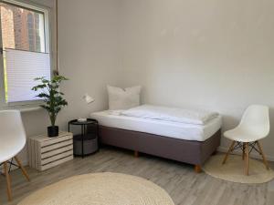a bedroom with a bed and two chairs and a window at Das MONTI - Superior in Stendal +5 photos