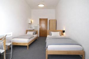 two beds in a room with a table and chairs at Villa Amarone in Mannheim