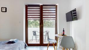 a bedroom with a sliding glass door with a table and chairs at Studio Fibra Barista in Rybnik