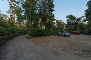 a parking lot with a car parked next to trees at Itsy Hotels Jammabane Cottage, 5 Minutes To Mountain View Coffee Plantation in Madikeri