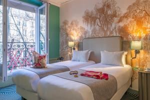 two beds in a room with a window at Hotel Avalon Paris Gare du Nord in Paris