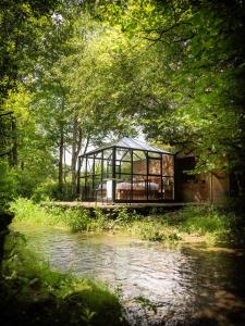 a glass house on a bridge over a river at Nids des Marais in Ciney