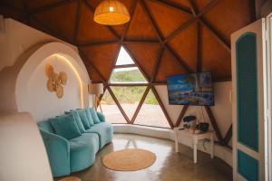 a living room with a blue couch and a large window at Cipó Cabanas in Santana do Riacho