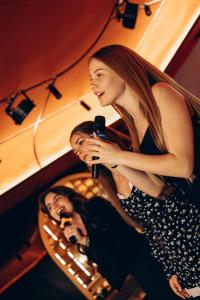 a woman singing into a microphone in front of a mirror at ARISTO Jacuzzi Hotel in Lviv
