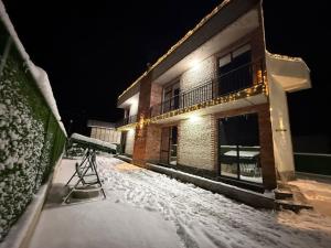 a snow covered street with a building at night at Villa Marhaba in Borjomi