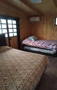two beds in a room with wooden walls at Casa Hostal Familiar Espacio SaTaNaMa in El Torreón