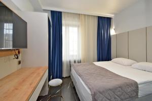 a bedroom with a large bed and blue curtains at Апарт-отель ЛЕВЕЛ Ереван, Ханджян 47 in Yerevan