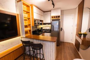 a kitchen with a bar with stools and a refrigerator at Flat Exclusivo studio cuiaba 702 in Cuiabá +3 photos