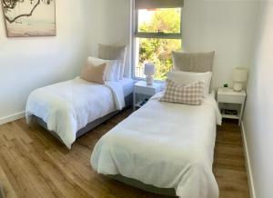 zwei Betten in einem Zimmer mit Fenster in der Unterkunft Simplicity Terrigal in Terrigal