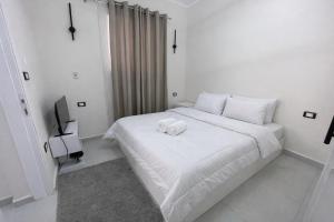 a white bedroom with a bed with two towels on it at Younis chalet in Dahab