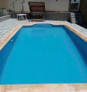 a large blue swimming pool with a table and a chair at Villa appartement jardin et piscine in Meknès
