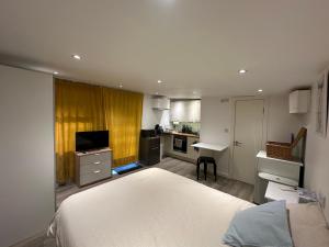 a bedroom with a white bed and a kitchen at Cosy, self-contained guest house in Thornton Heath